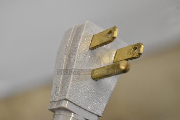 Close-up of a 3-prong electrical plug, textured white plastic with brass pins.