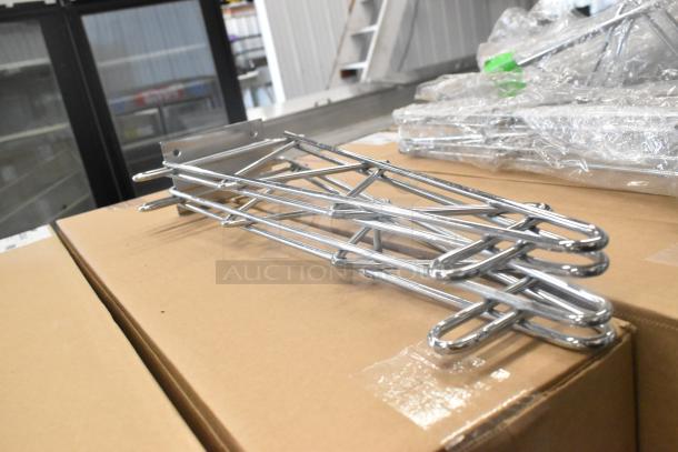 Lot of 9 brand new scratch and dent chrome finish shelf brackets, layered on a cardboard box.
