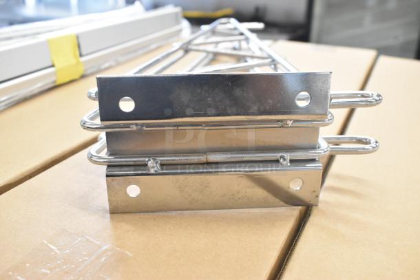 Lot of 9 brand new chrome finish shelf brackets, slight scratch and dent. Stacked on cardboard, ready for use.