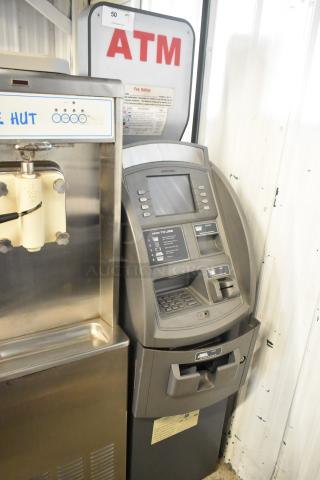 Hyosung metal floor style ATM, gray, with digital screen and keypad, fee notice sign on top, in used condition.