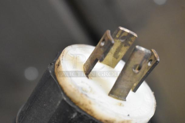 Close-up of a plug component of Taylor 441-33 soft serve ice cream machine, showing metal prongs and a plastic encasing.