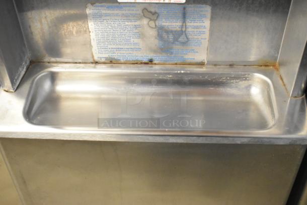 Taylor 441-33 stainless steel commercial soft serve ice cream machine. Features visible wear and cleaning instructions label.