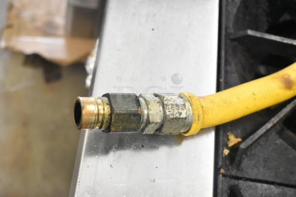 Close-up of a yellow gas hose fitting for a Garland SunFire stainless steel commercial range. Slightly worn condition.