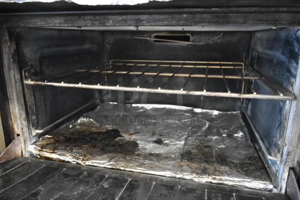 Interior of Garland SunFire commercial oven showing wire rack and foil-lined base, indicating heavy use and wear.