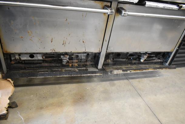 Garland SunFire stainless steel commercial gas 10-burner range with 2 ovens, over shelf, and backsplash. Visible wear on surfaces.