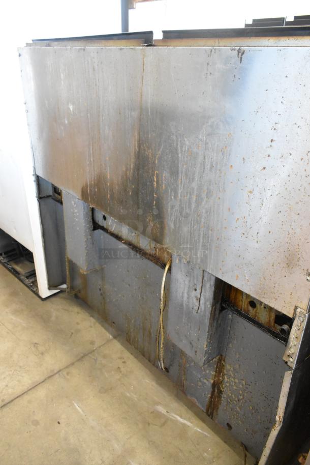 Garland SunFire stainless steel commercial gas range, features 10 burners, 2 ovens, over shelf, and backsplash, signs of wear.
