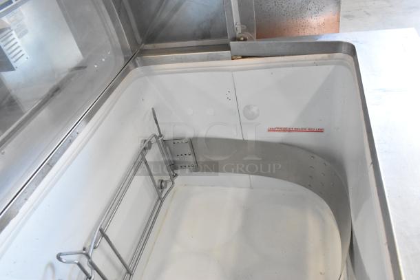 Metal commercial ice cream dipping cabinet with bucket collars, stainless steel, interior view showing bucket support rack and label "KEEP PRODUCT BELOW RED LINE".