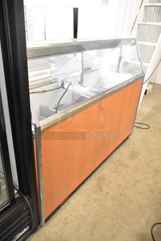 Metal commercial ice cream dipping cabinet with bucket collars, featuring glass display, wooden panels, in used condition.