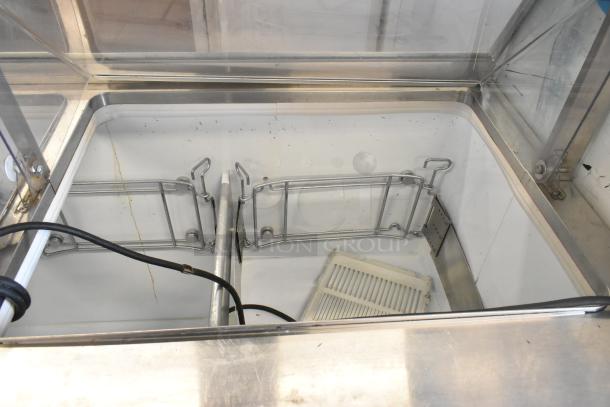 Metal commercial ice cream dipping cabinet with bucket collars, stainless steel, interior view, used condition.