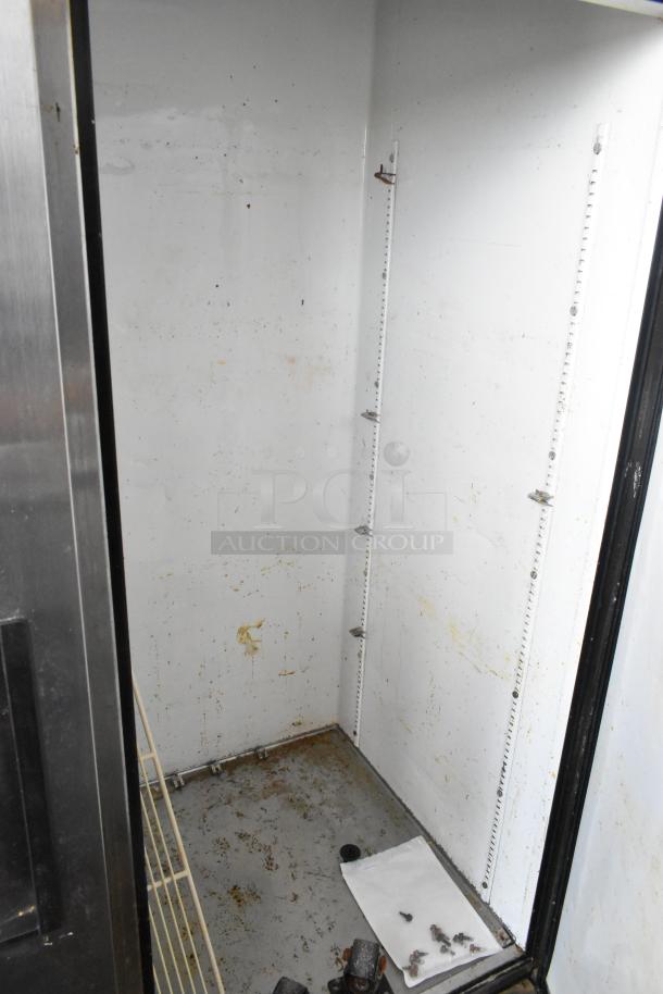 True T-49 stainless steel commercial cooler interior, showing used condition with shelving brackets and visible wear.