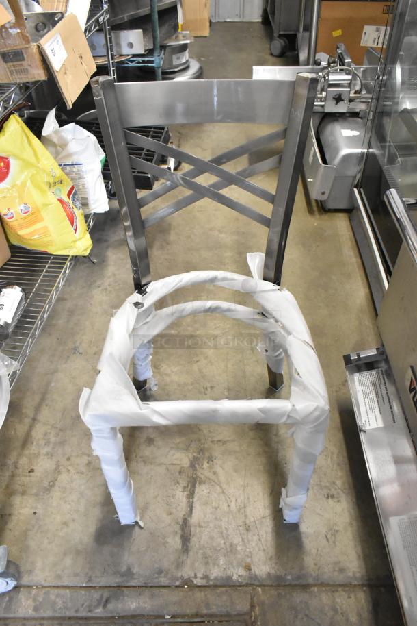 Brand new gray metal dining chair frame with cross back design, partially wrapped. Scratch and dent condition.