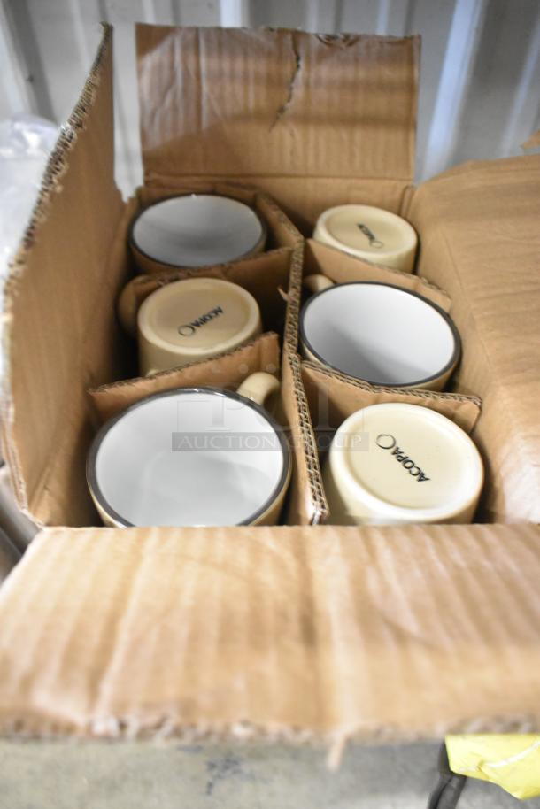 Box of 12 brand new Acopa ceramic mugs, beige with black rims, labeled "Acopa" on the bottom, in original packaging.