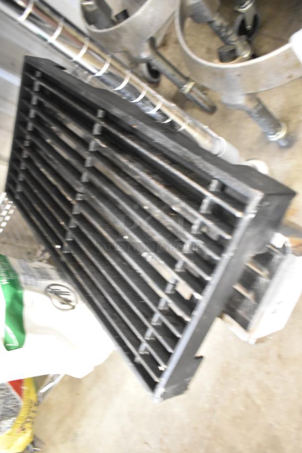 Close-up of metal charbroiler grate with multiple horizontal bars, industrial setting. Condition shows signs of use.