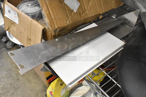 Lot of various items including metal brackets, cushions, and a damaged cardboard box on a metallic shelf.