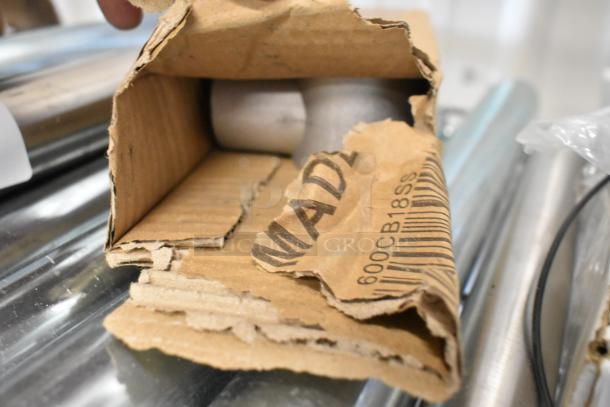 Lot of 10 metal legs, partly visible in worn cardboard packaging. Markings: "600CB18SS." Condition appears unused.