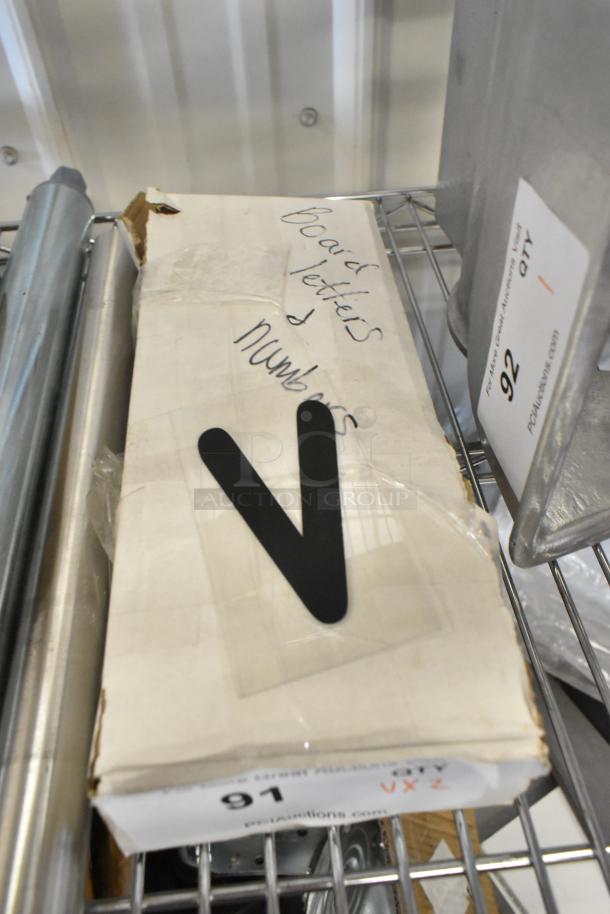 Box labeled "Board letters & numbers" containing fish deli tag wheel and sign letters, item 91 in auction. Box is slightly worn.