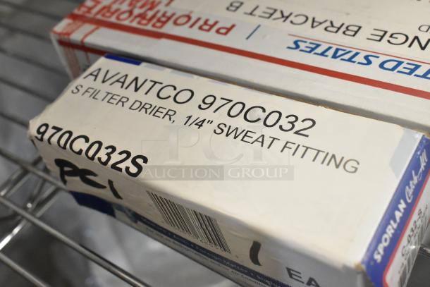 Box labeled "Avantco 970C032S Filter Drier, 1/4" Sweat Fitting" on a shelf, part of a mixed auction lot.