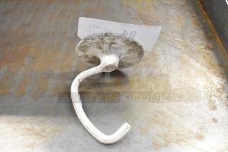 Metal dough hook attachment for KitchenAid mixer, showing signs of wear on a metallic surface.