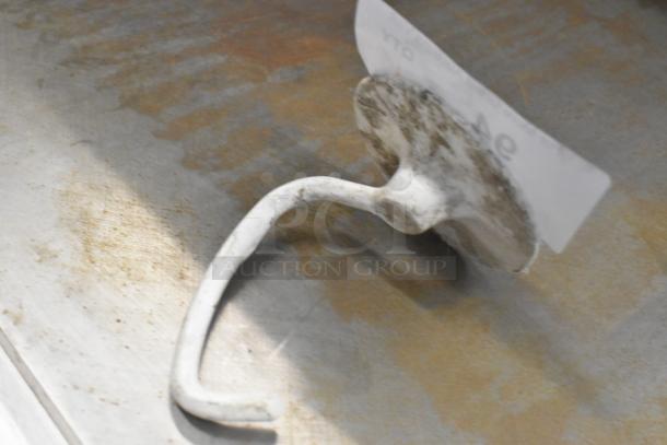 Metal dough hook attachment for KitchenAid mixer, slightly worn condition, curved design, ideal for kneading dough.