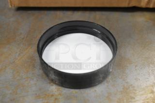 Box of black circular plastic lids, shown on industrial surface. Lids appear new, no visible markings or labels.