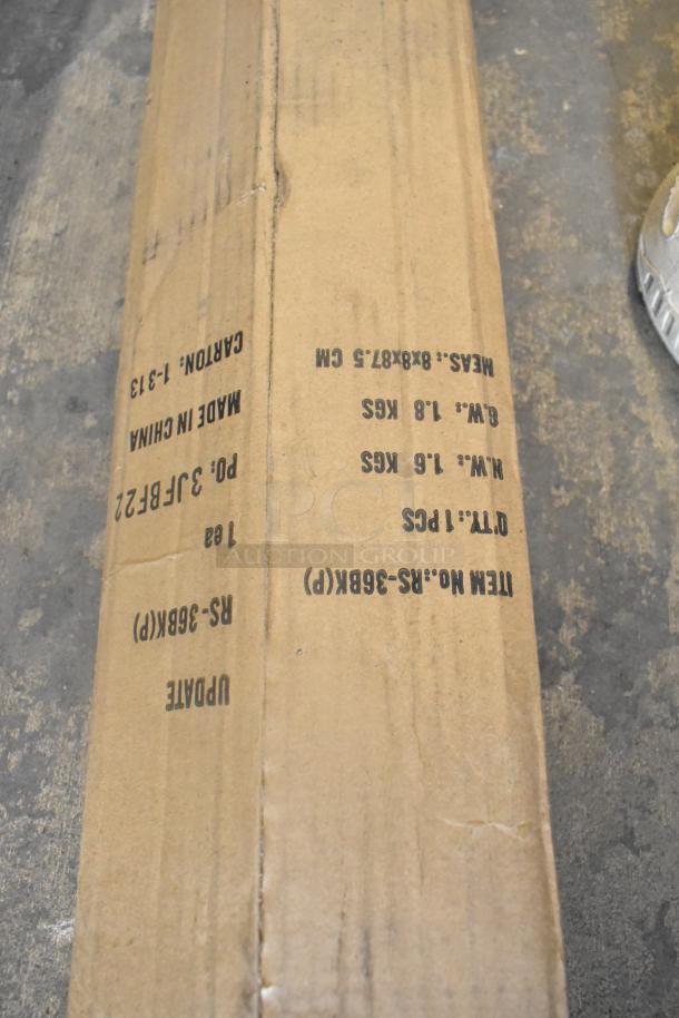 Cardboard box with markings for Update RS-36BK Stanchion. Item is new, labeled "scratch and dent". Dimensions: 8x8x87.5 cm.