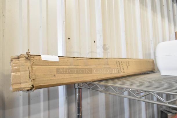 Cardboard box on metal shelf containing a brand new Update RS-36BK stanchion. Box shows some wear.