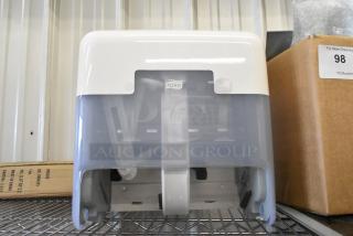 Tork gray and white poly wall mount paper towel dispenser, sturdy condition, clear front cover, with Tork logo visible.