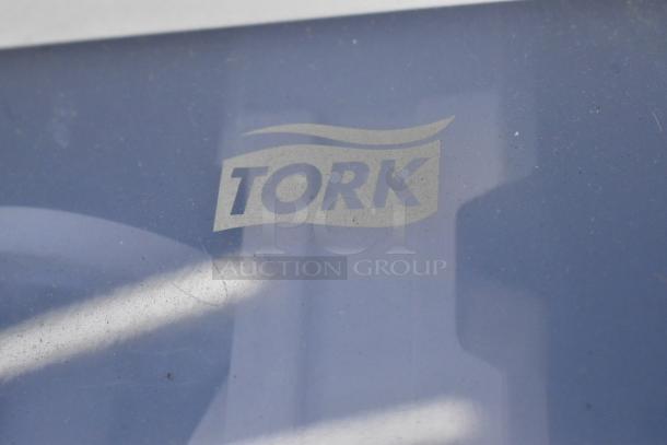 Tork gray and white poly wall mount paper towel dispenser with visible Tork logo on front panel. Suitable for commercial use.