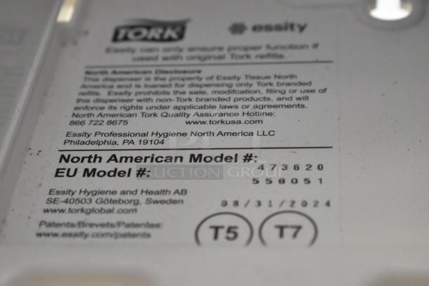 Tork gray and white poly wall mount paper towel dispenser, featuring North American model info, visible Tork and Essity branding.