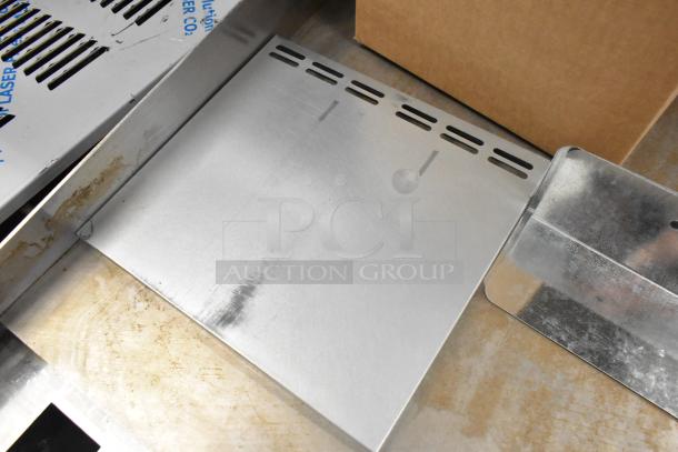 Box of assorted metal pieces, including a variety of flat and bent sheets, showing cut-out designs and industrial finish.