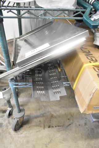 Lot of metal panels on a cart, various sizes and shapes, some with ridges. Includes a cardboard box labeled "820mm". Small tag "105".