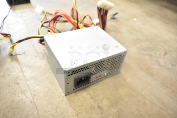 AT-265SFX power supply, silver casing, multiple cables, fan vent, good condition, standard connector visible.