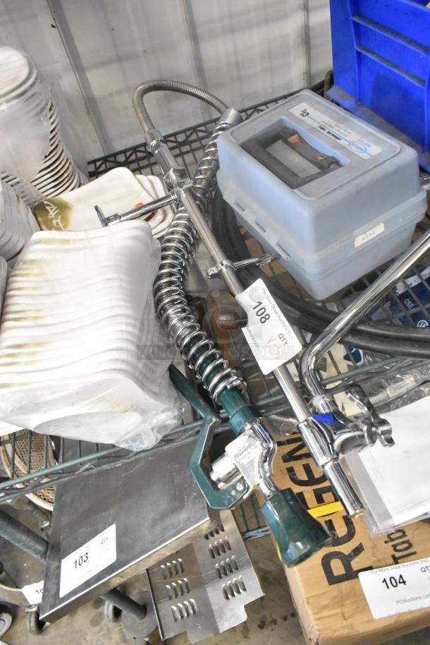 Lot of various items on metal cart including booster seat, spray nozzle attachment, and assorted kitchenware. Auction tags visible.