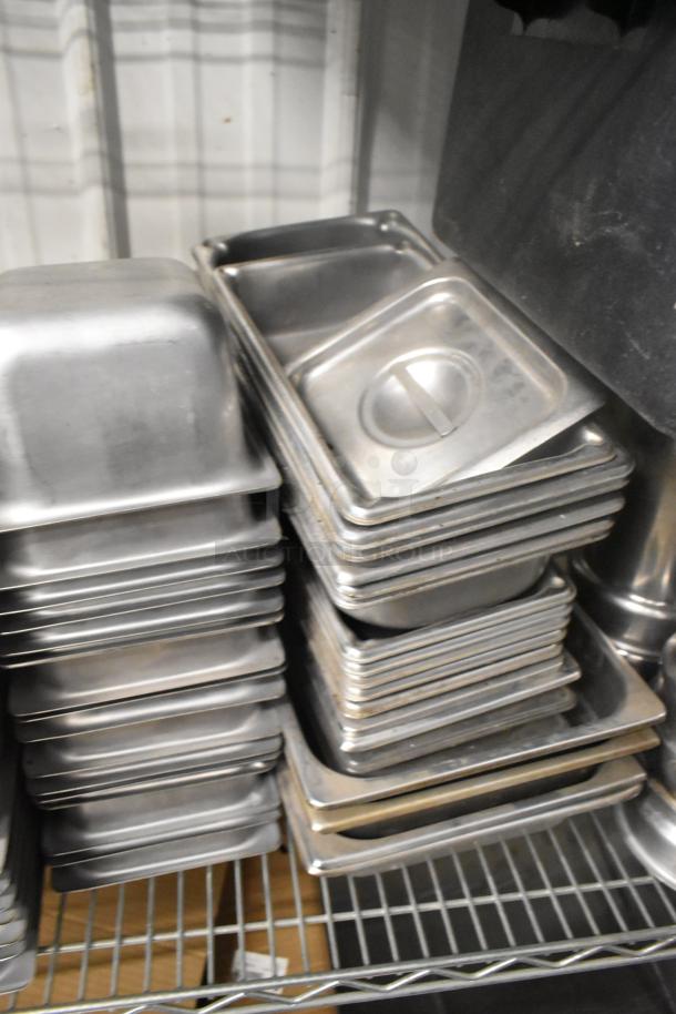 Tiered lot of stainless steel drop-in bins, various sizes, stacked on a shelf. Used condition, ideal for kitchen storage.