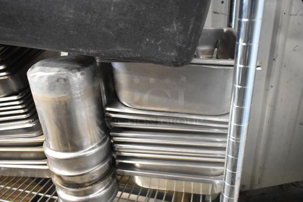 Stack of stainless steel drop-in bins and inserts on a metal shelf, showing signs of wear. Ideal for storage or kitchen use.