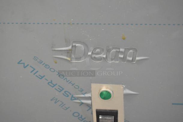 Stainless steel panel featuring "Dean" text and a green indicator light, part of the Frymaster SR114ESD fryer. Film cover visible.