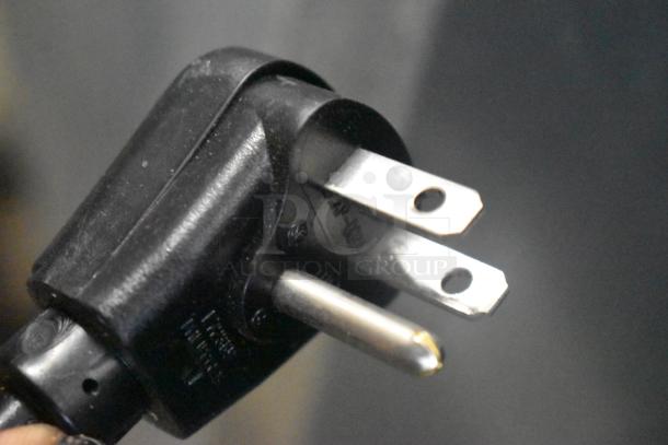 Close-up of a black, three-prong power plug for a Scotsman HID312A-1A ice machine, showing prongs and plug casing.