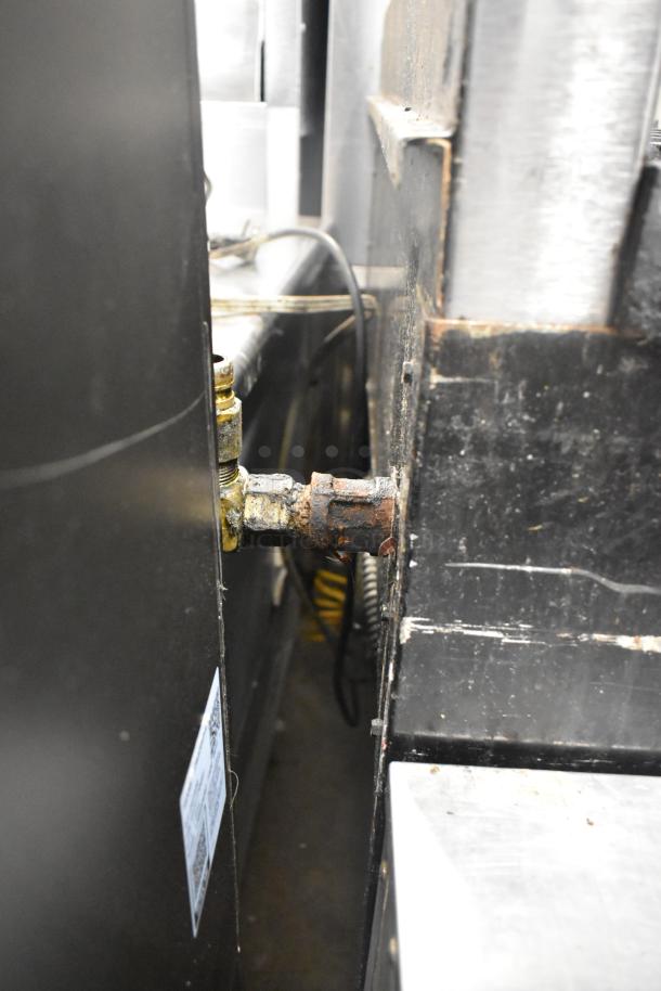 Back view of Montague stainless steel commercial gas-powered 4-burner range with attached oven, showing gas connection detail.
