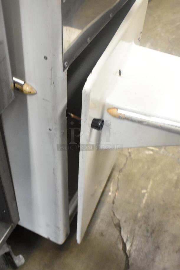 Metal commercial floor-style citrus juicer on casters, 115 volts, 1 phase. Visible door panel; commercial-grade construction.