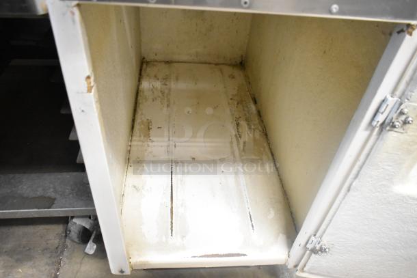 Metal commercial floor-style citrus juicer on casters, dirty condition, 115 volts, 1 phase; interior view.