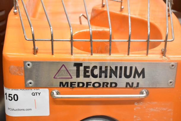 Metal commercial floor-style citrus juicer, 115V, 1 phase, with commercial casters. "TECHNIUM, MEDFORD NJ" label visible.