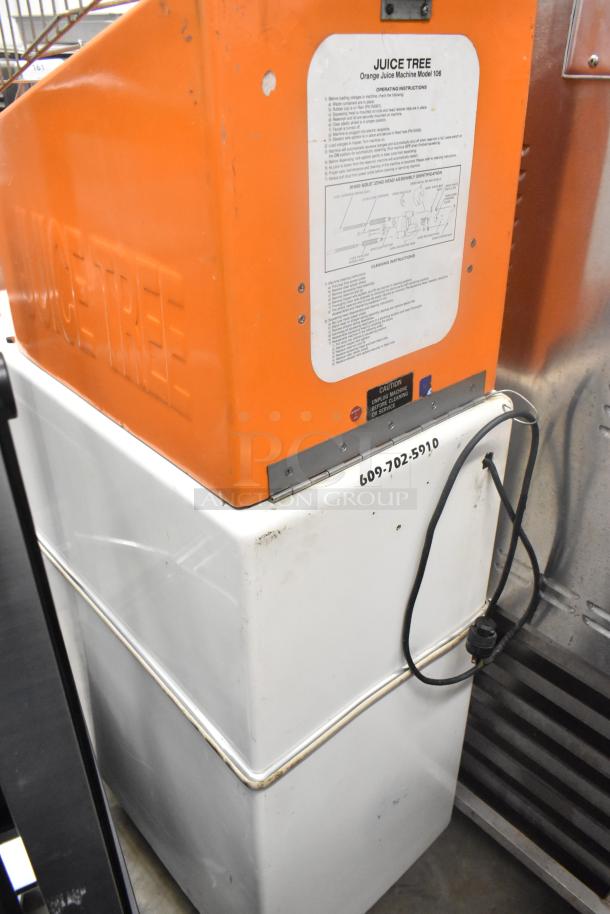 Metal commercial citrus juicer on casters, 115 volts, features "JUICE TREE" branding, visible operating instructions.