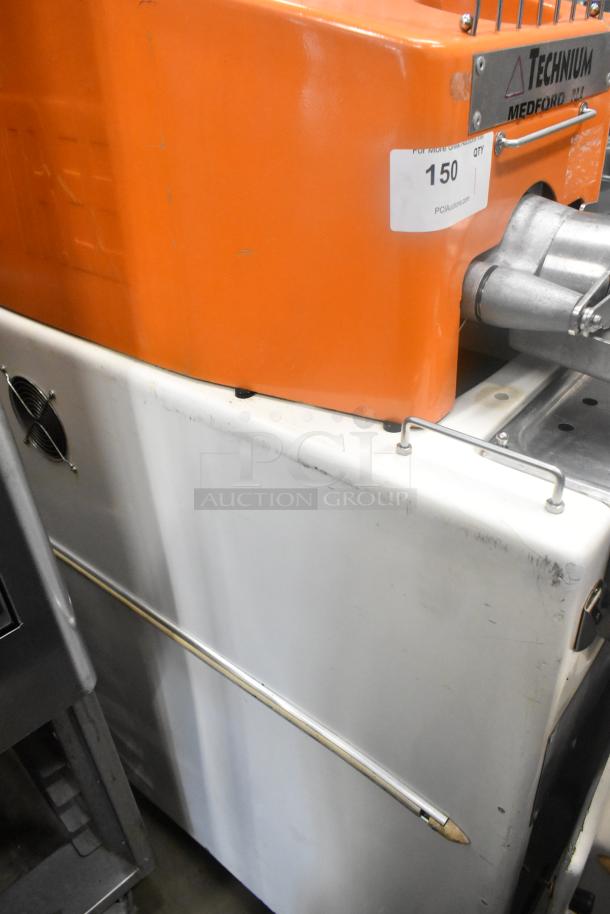 Metal commercial citrus juicer on casters, orange and white, Model Technum. 115V, 1 phase. Auction label visible.

