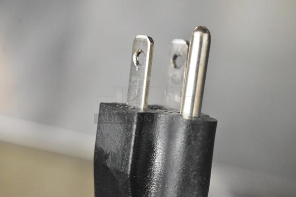 Close-up of a black electrical plug with two prongs and a metal ground pin.