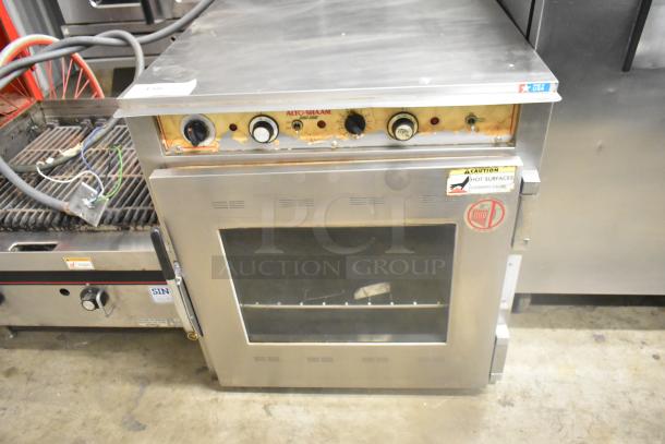 Alto Shaam stainless steel commercial Cook N Hold oven with visible dials and controls; shows wear on control panel.