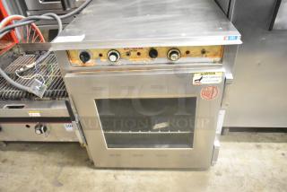 Alto Shaam stainless steel commercial Cook N Hold oven with visible dials and controls; shows wear on control panel.