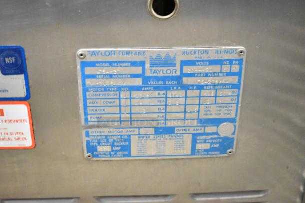 Taylor 754-27 stainless steel commercial soft serve ice cream machine label showing volts, amps, and serial number details.