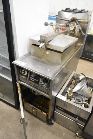 Henny Penny 600 stainless steel pressure fryer on commercial casters, 80,000 BTU. Shows signs of use; control panel visible.