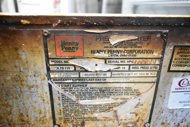 Henny Penny 600 Pressure Fryer label showing model, 80,000 BTU, volts, and instructions. Rust visible on the surface.