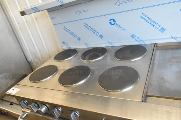 Imperial stainless steel commercial 6-burner electric hot plate range with griddle, 2 ovens, over shelf, and backsplash.